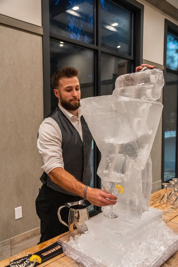 Bartender pouring a cocktail through an ice sculpture